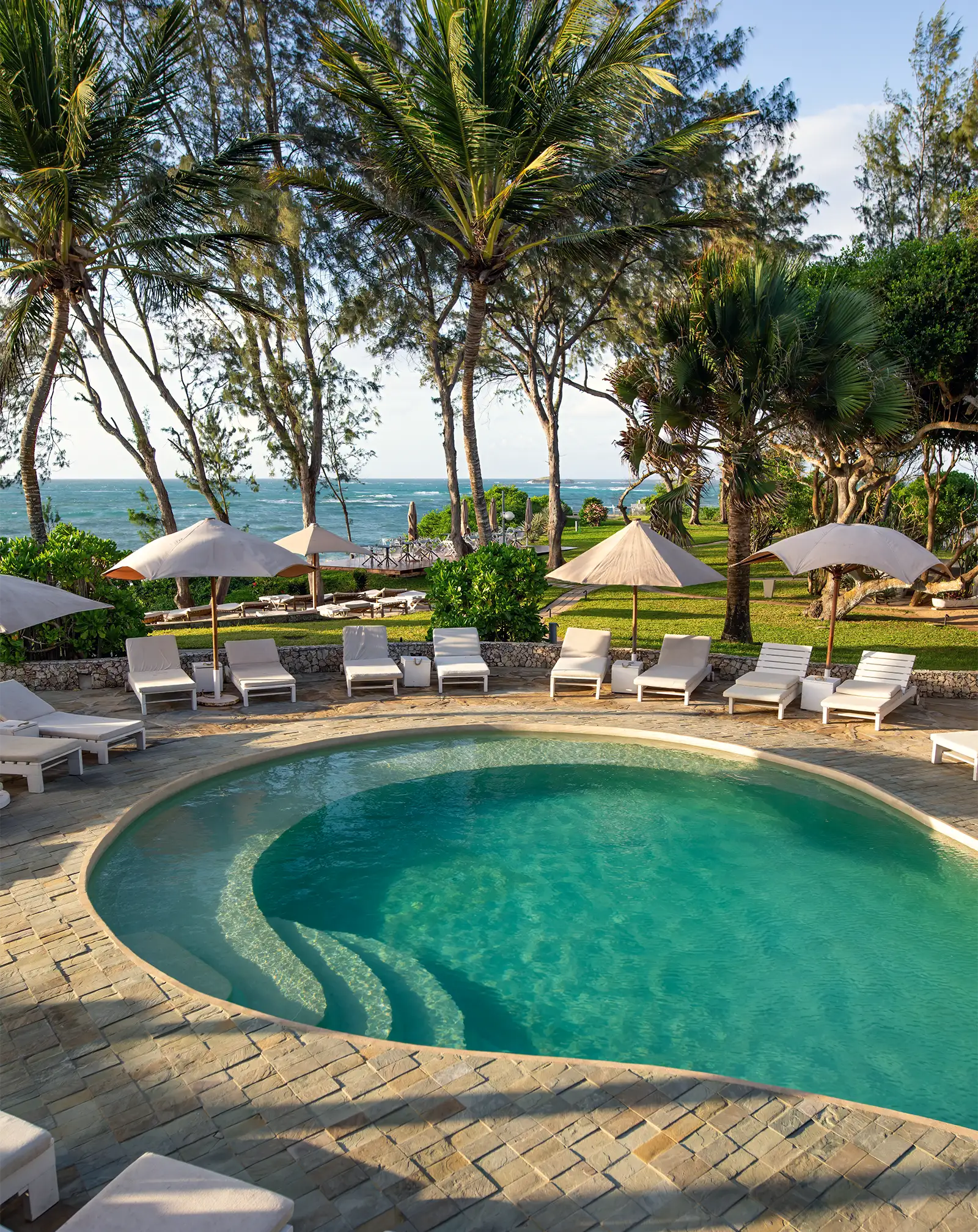 Main swimming pool surrounded by tropical gardens and overlooking the ocean at Kobe Suite Resort