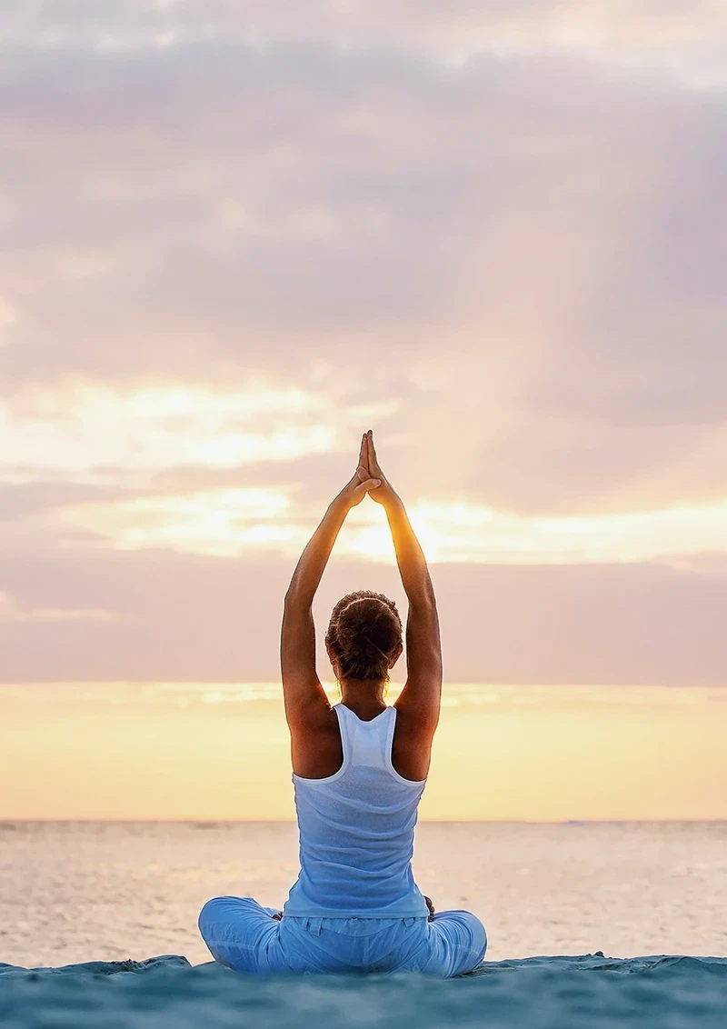 Woman practicing yoga at sunrise by the Indian Ocean in Watamu