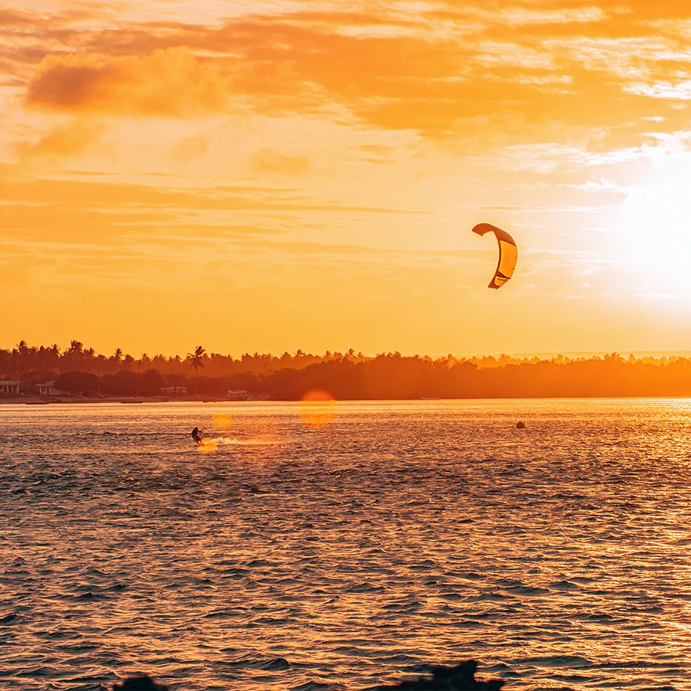 Kitesurfer riding across the water at sunset in Watamu, Kenya