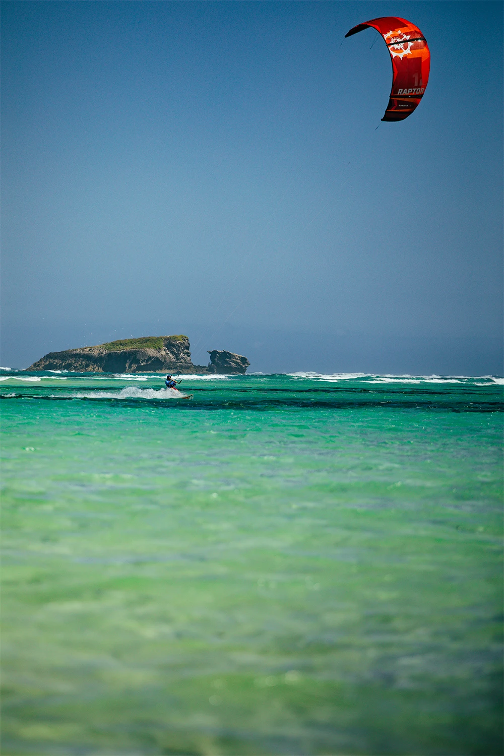 Kitesurfer riding in the turquoise waters of Watamu with a coastal island in the background