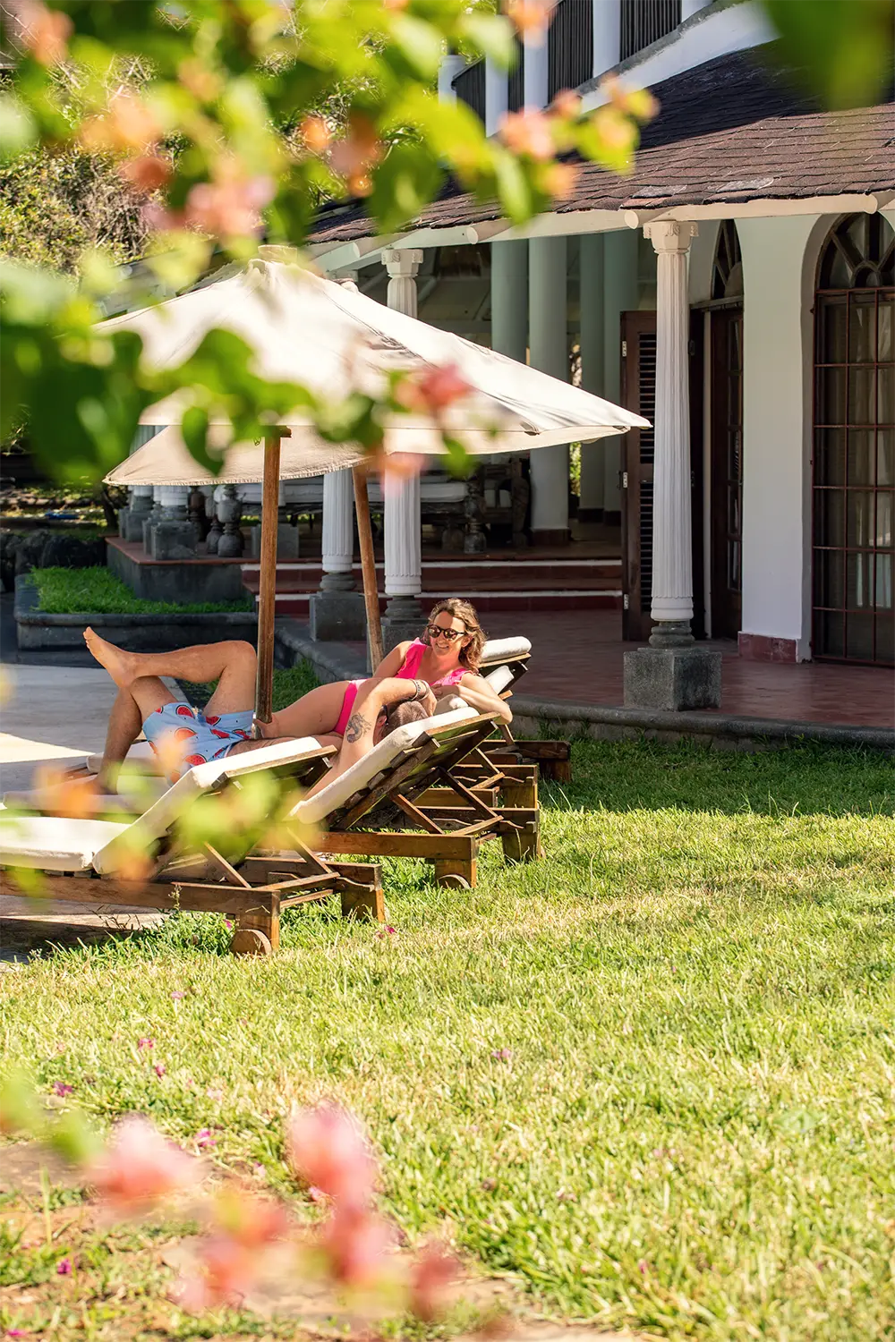 Couple relaxing on sun loungers in the tropical gardens at Kobe Suite Resort