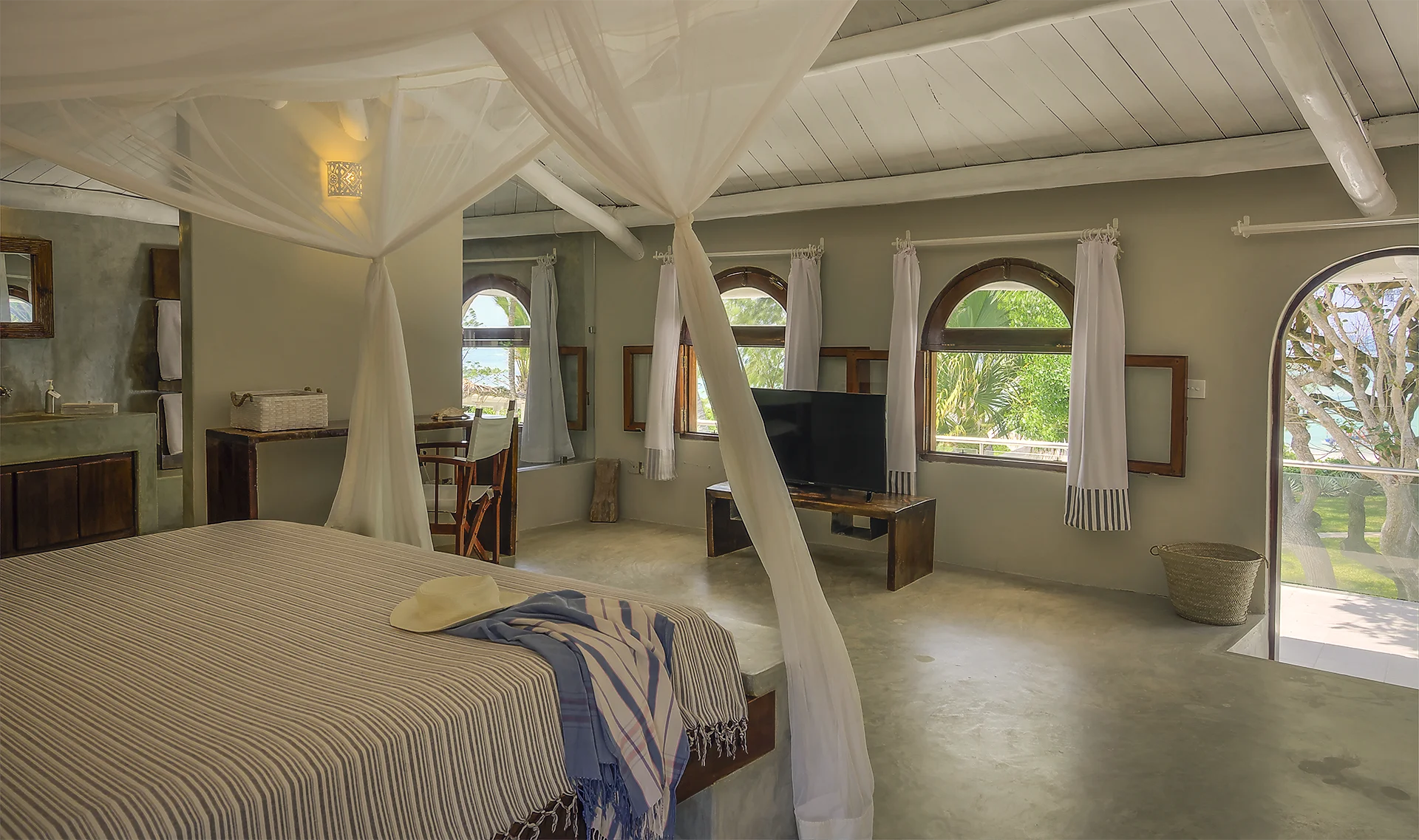 Deluxe Ocean View Suite bedroom with four-poster bed and tropical garden views