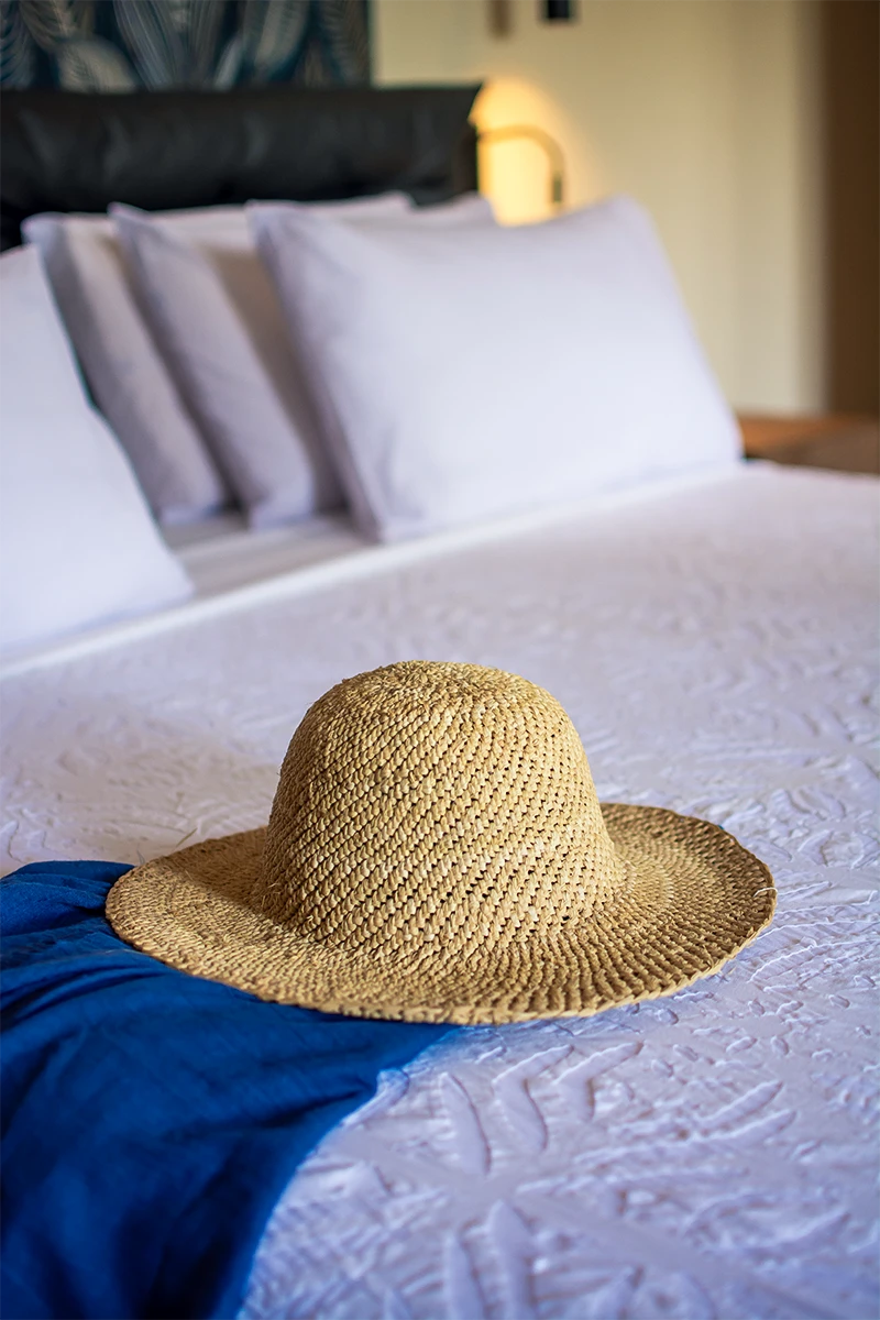 King-size bed with woven sun hat in the Presidential Ocean View Suite