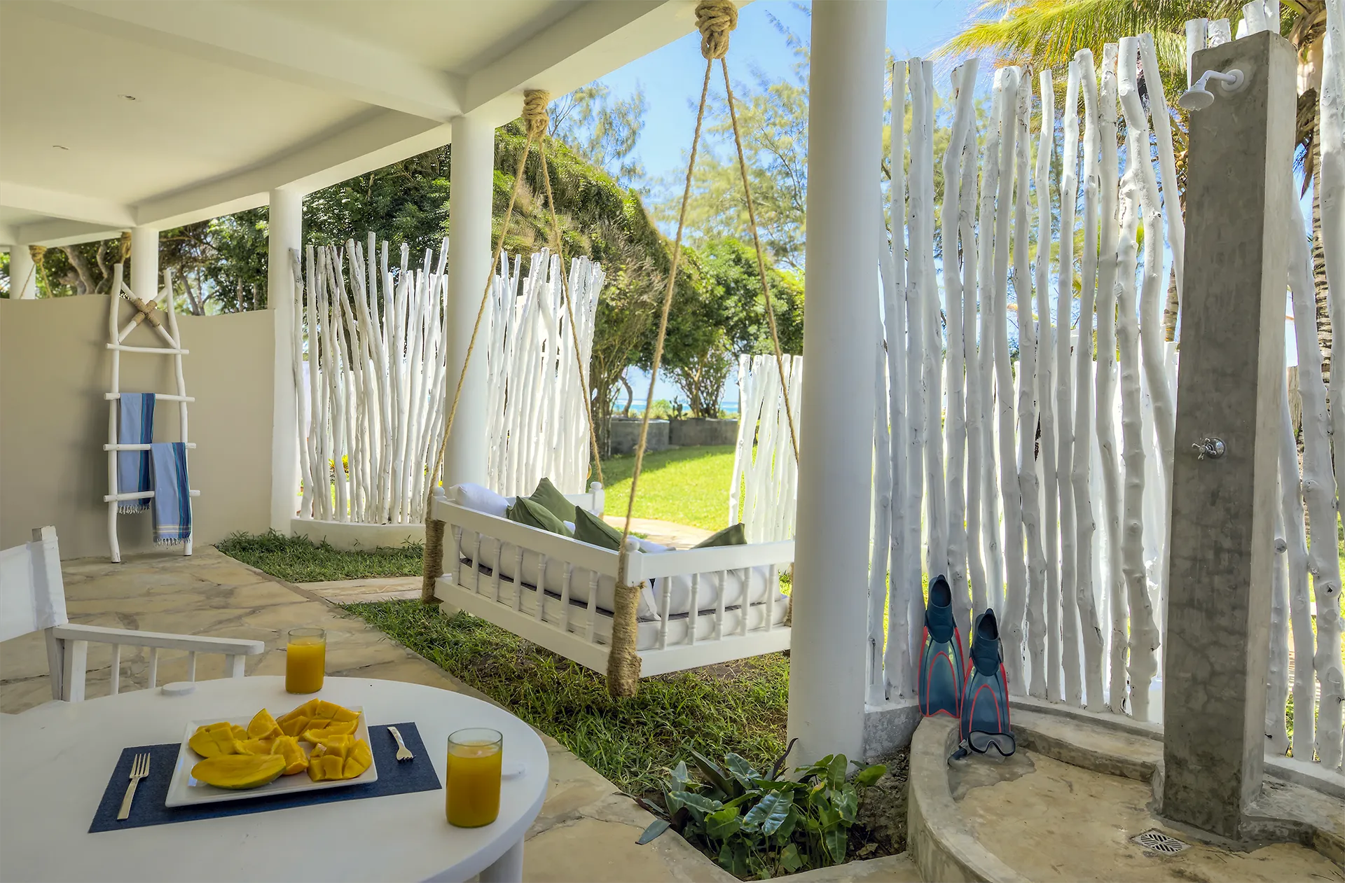 Private outdoor area with hanging daybed, dining table and tropical garden views