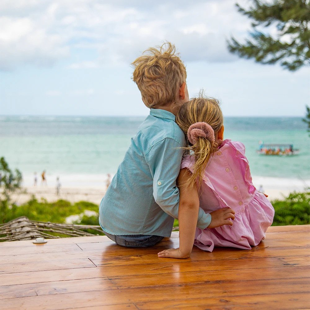 Two children sitting together overlooking the beach and Indian Ocean in Watamu