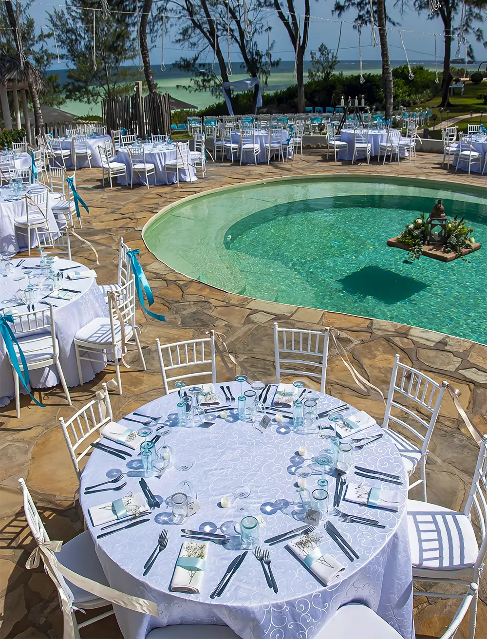 Wedding banquet with round tables set around the pool at Kobe Suite Resort