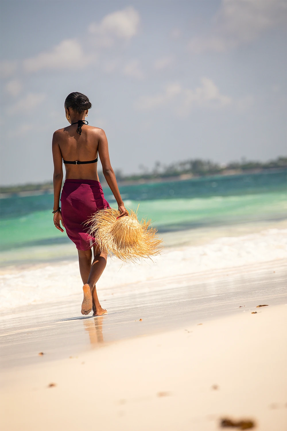 Woman walking along the white sandy beach in Watamu, Kenya